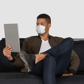 A man sitting on a couch wearing a face mask