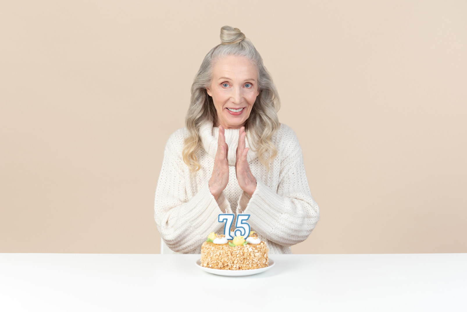 Old woman sitting at at the table with cake for her seventy fifth birthday
