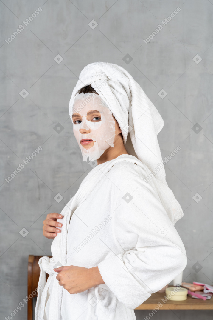 Side view of a woman in bathrobe with a face mask on