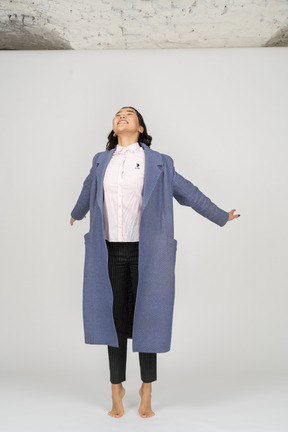 Excited woman in coat stretching up on toes