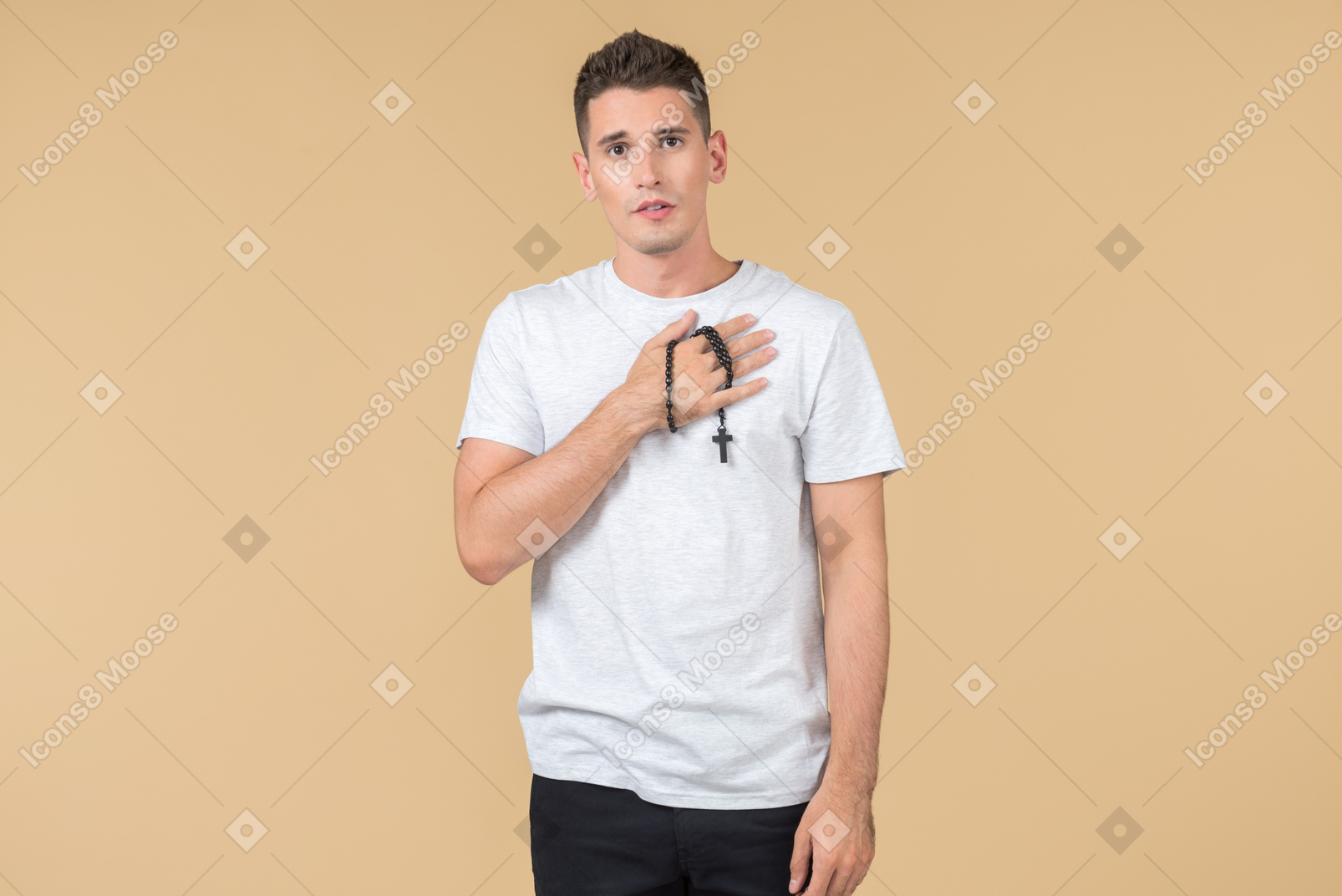 Young guy with prayer beads on his hand holding his hand on a chest