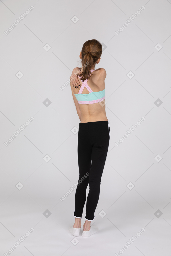 Vista traseira de uma adolescente em roupas esportivas tocando seu ombro