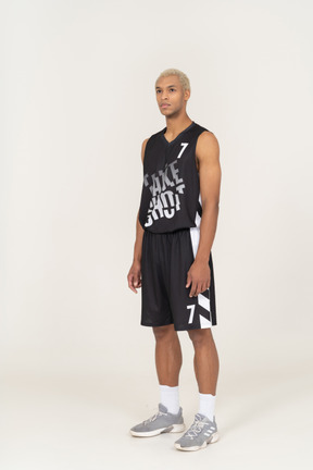 Three-quarter view of a young male basketball player standing still