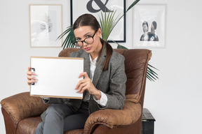 A business woman sitting in a chair and holding a blank board