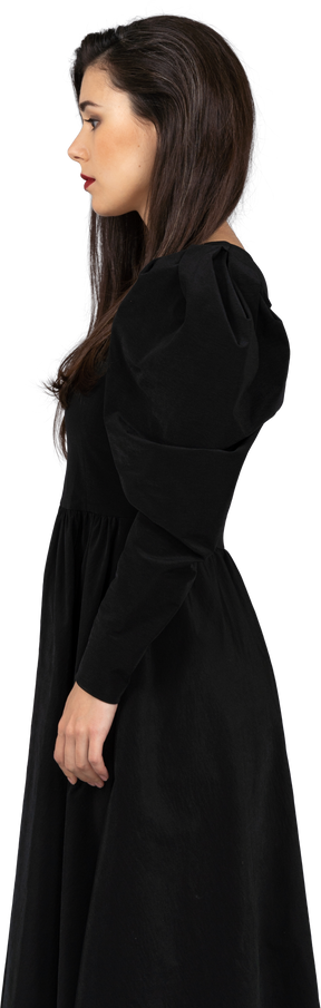 一位年轻的女士，穿着黑裙子站着不动的侧视图