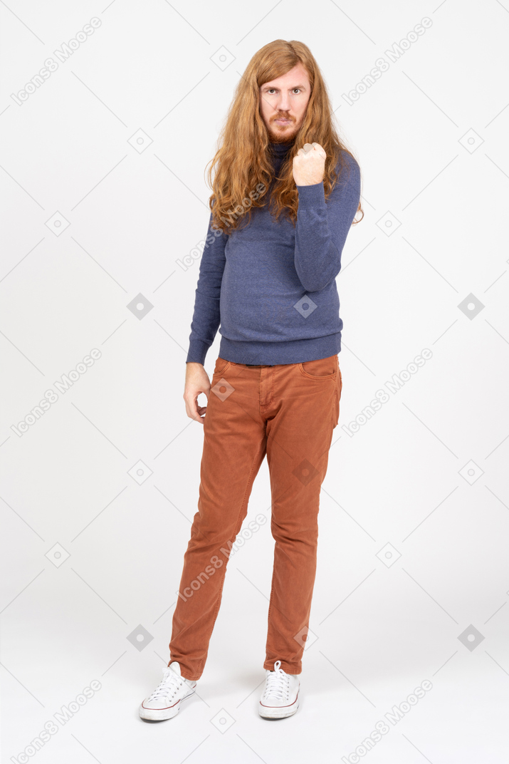 Vista frontal de um jovem em roupas casuais, olhando para a câmera e mostrando o punho