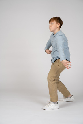 A young boy walking and swinging his arms