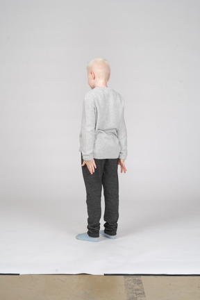 Three-quarter back view of a boy standing