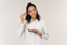 Young woman putting on eyeshadows