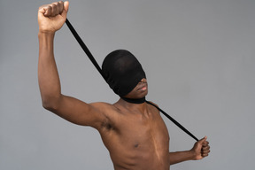 Young man being blindfolded and choked with black tights
