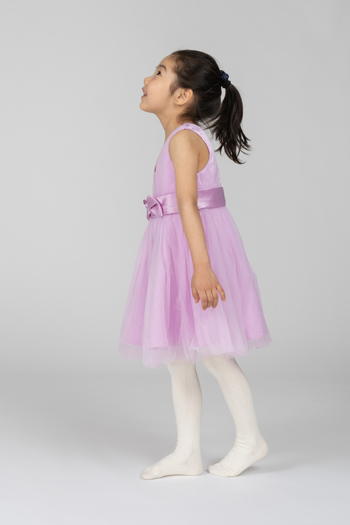 Side view of a girl in a pink dress looking up