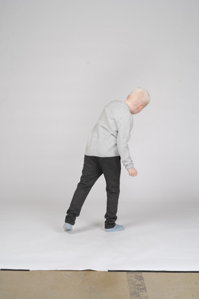 Back view of a boy in casual clothes bending down