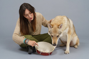 В полный рост женщина-хозяин и ее собака нюхают барабан