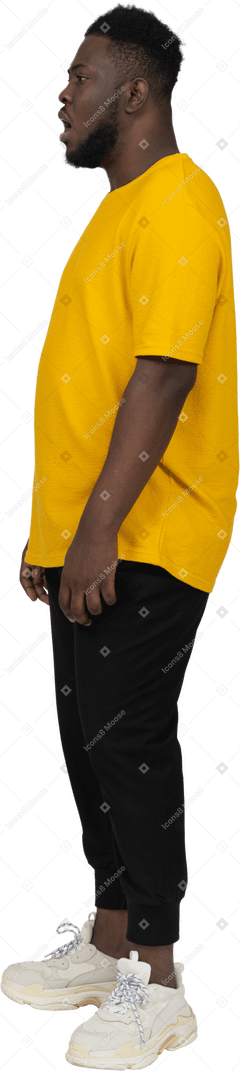 Vista laterale di un giovane uomo dalla pelle scura scioccato in maglietta gialla