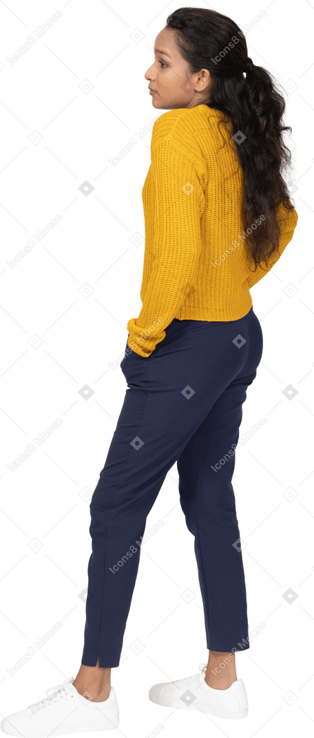 Side view of a girl in casual clothes posing with hands in pockets