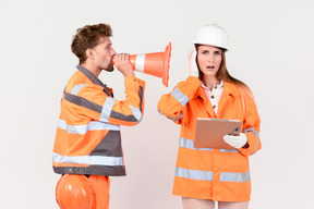 Operaio stradale maschio che grida in cono alla sua collega