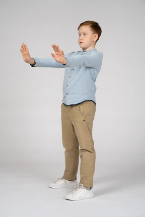 Side view of a boy standing with extended arms