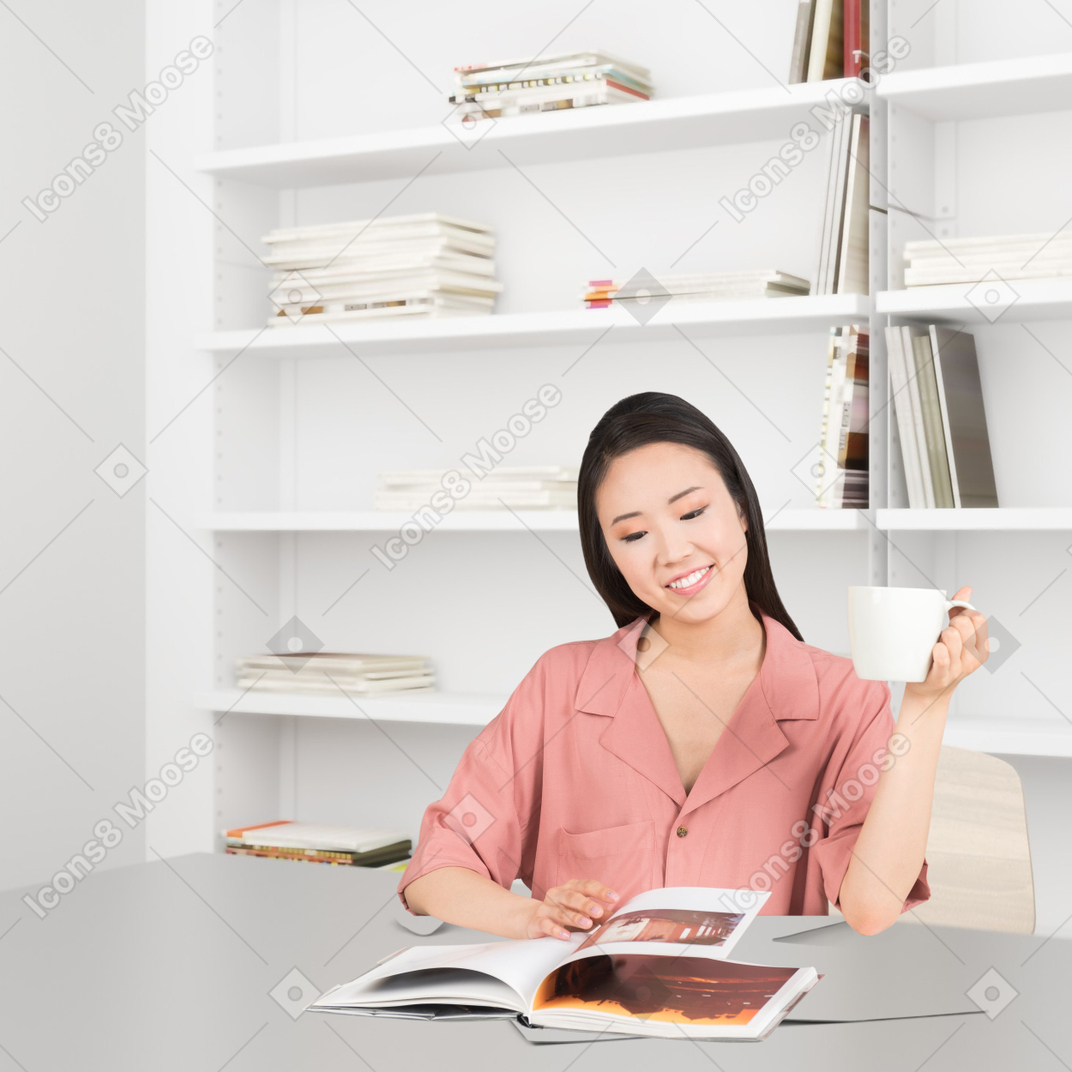 A woman sitting at a table with a book and a cup of coffee