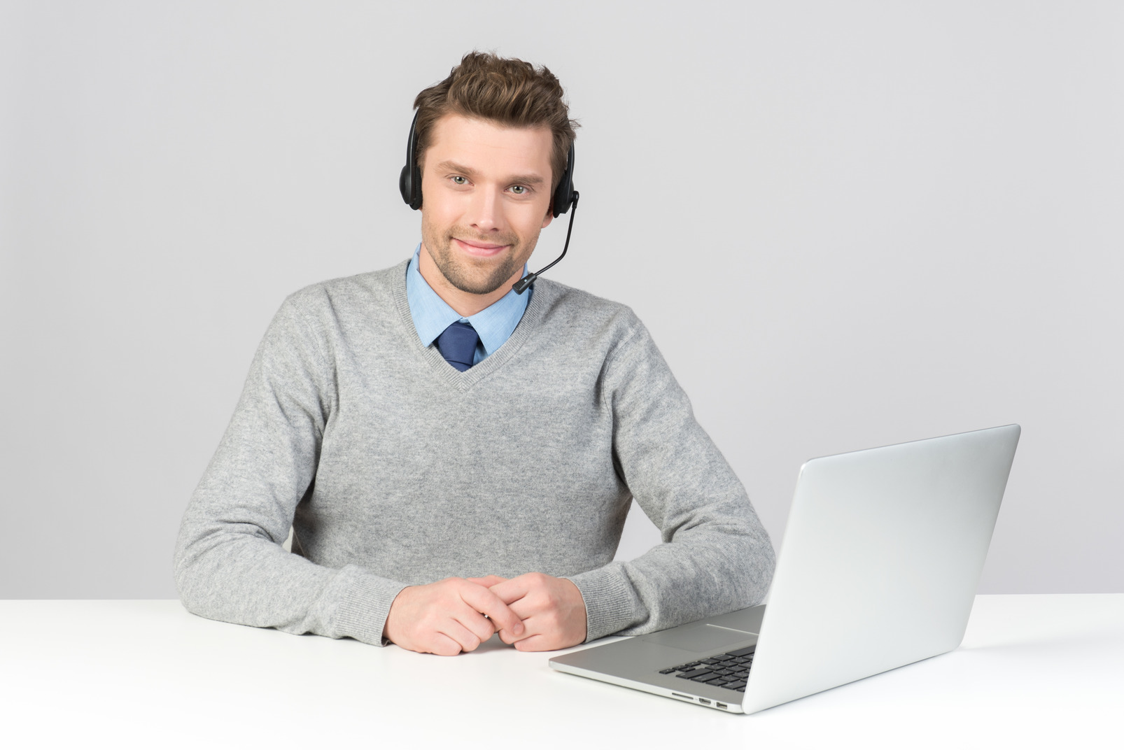Call center agent sitting at office desk with hands folded