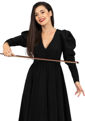 一位身穿黑色连衣裙、手持弓的高兴的年轻女士的前视图