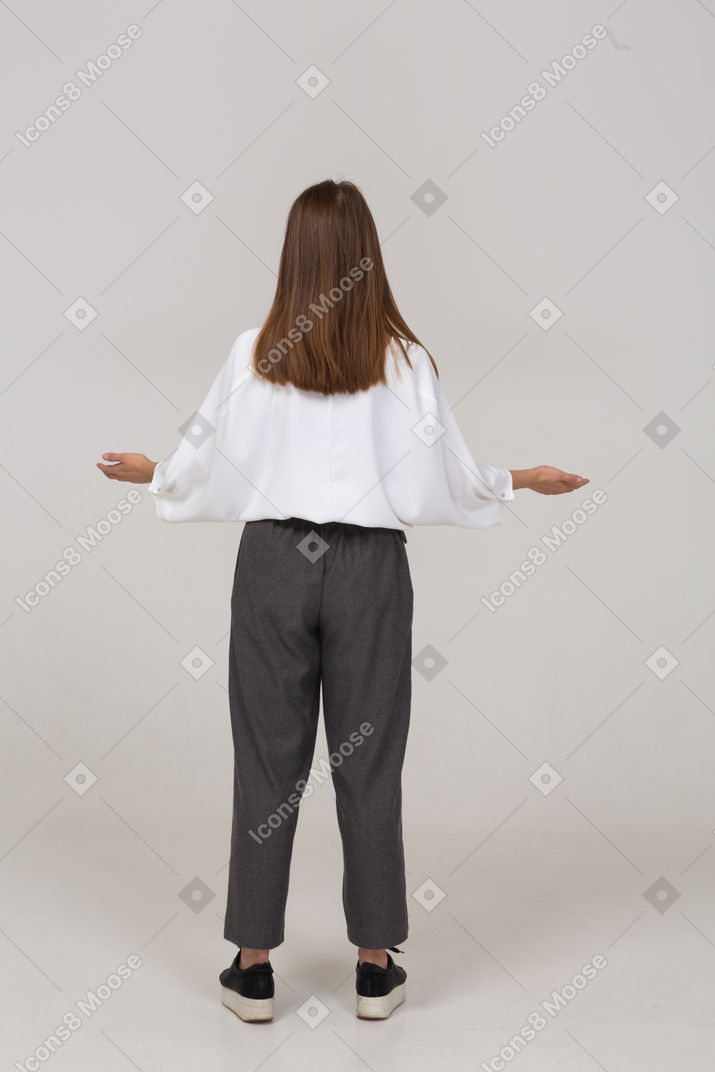 Vista posteriore di una giovane donna in abiti da ufficio che allarga le mani