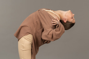 Young woman bending backwards with hand on shoulder
