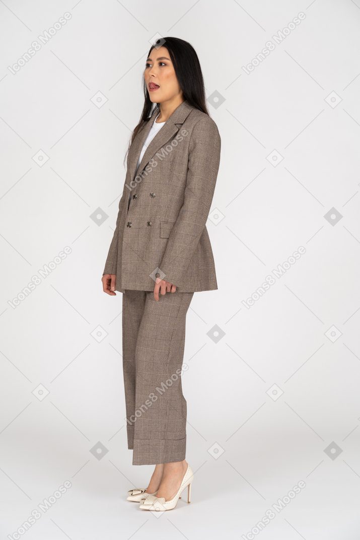 Dreiviertelansicht einer jungen dame im braunen business-anzug, die sich die lippen leckt