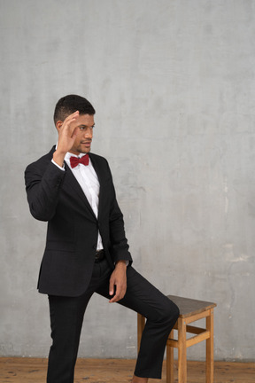 Front view of a man in black suit waving hello