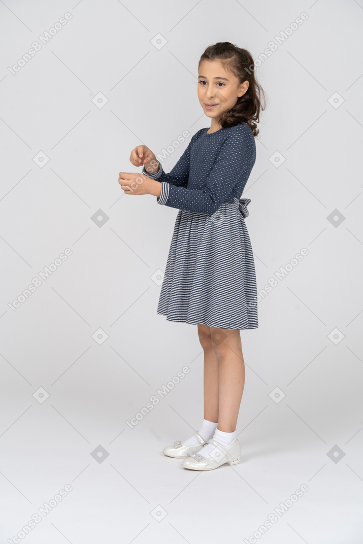 Three-quarter view of a girl smiling with a holding gesture