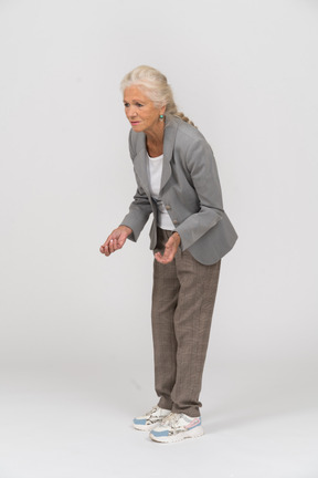 Seitenansicht einer alten dame im anzug, die sich bückt und etwas erklärt