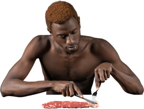 一个年轻的非洲人切肉的前视图