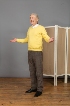 Vista de três quartos de um velho sorridente perto da tela levantando as mãos
