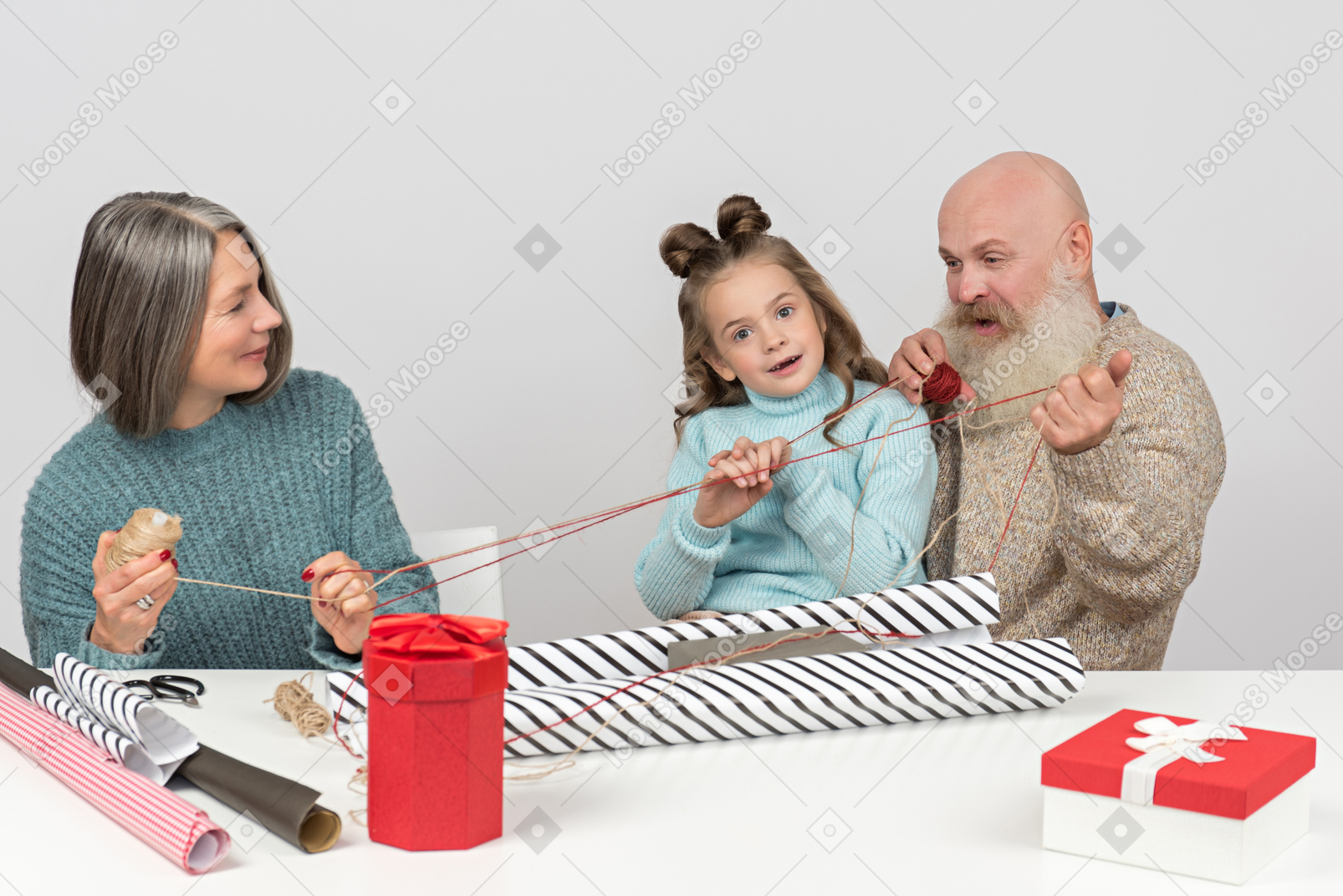 Grandparents and granddaughter holding threads while wrapping gifts
