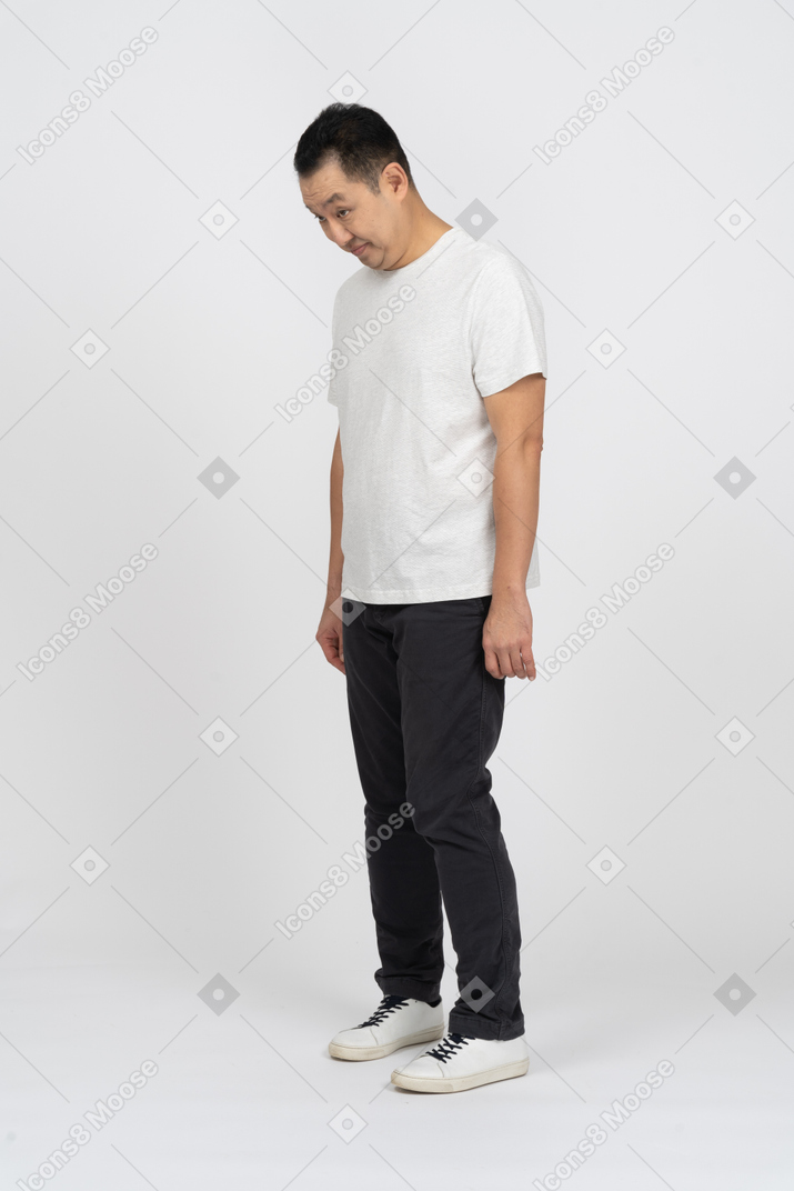 Man in casual clothes standing with head bent down