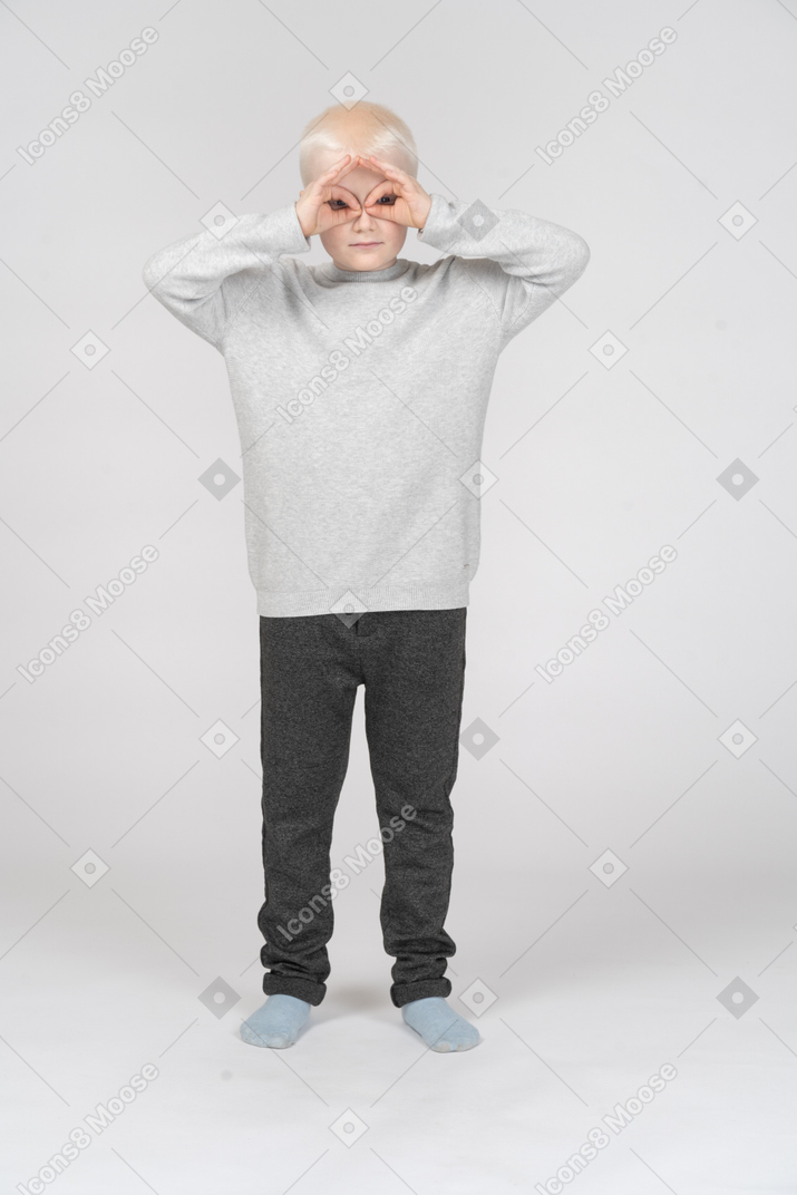 Garotinho fazendo gesto de binóculos com as mãos