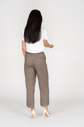 一位年轻的女士，穿着马裤和t恤伸出她的手的四分之三后视图