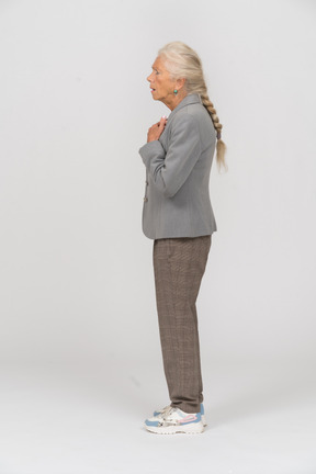 Impressed old lady in suit standing in profile