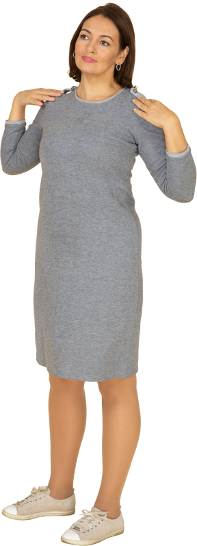 Vista frontale di una donna in abito grigio in piedi con le mani sulle spalle