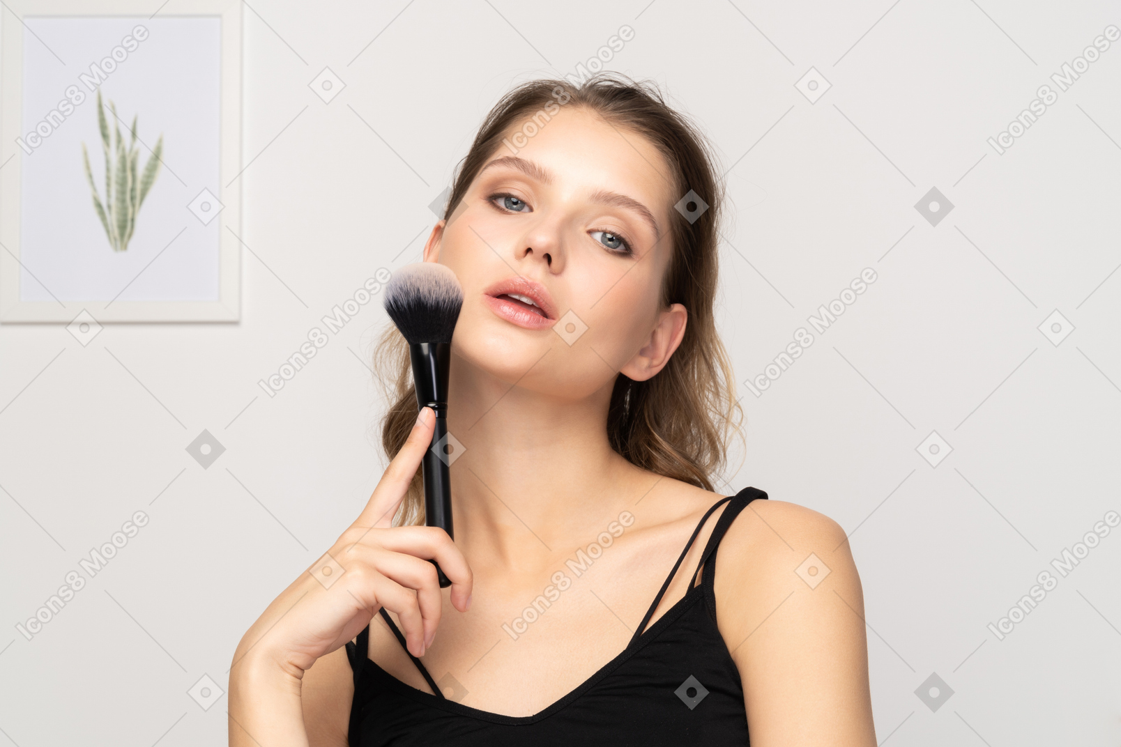Vista frontale di una giovane donna sensuale con in mano un pennello da trucco
