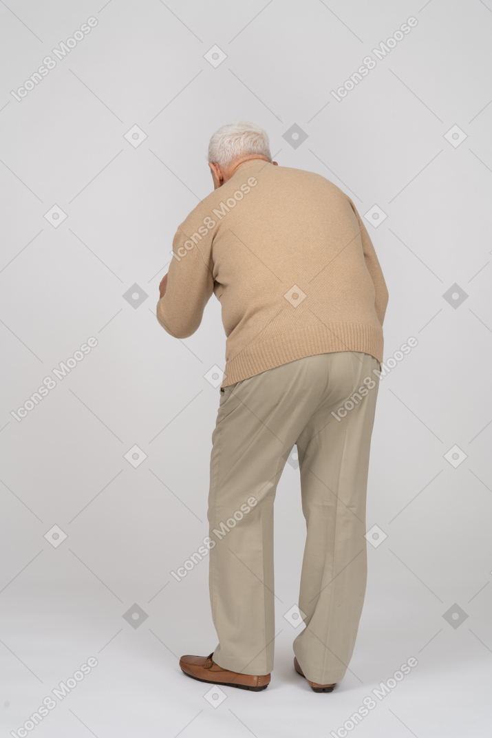 伸ばした腕で立って何かを説明するカジュアルな服装の老人の背面図