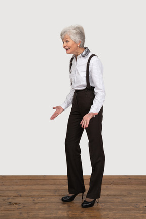 Three-quarter view of a smiling gesticulating old lady in office clothing