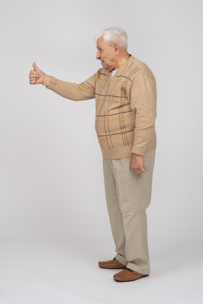 Вид сбоку на старика в повседневной одежде, показывающего большой палец вверх