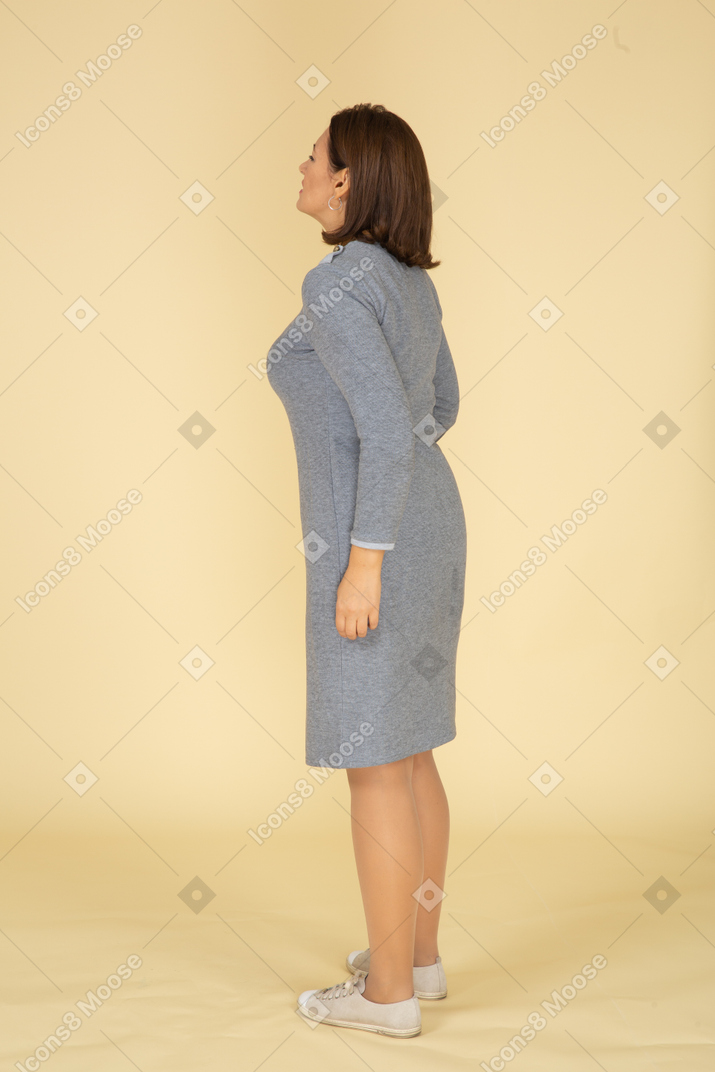 Vista lateral de uma mulher de vestido cinza sofrendo de dor de estômago