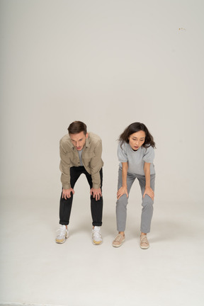 Jeune homme et femme impuissants debout avec les mains sur les genoux