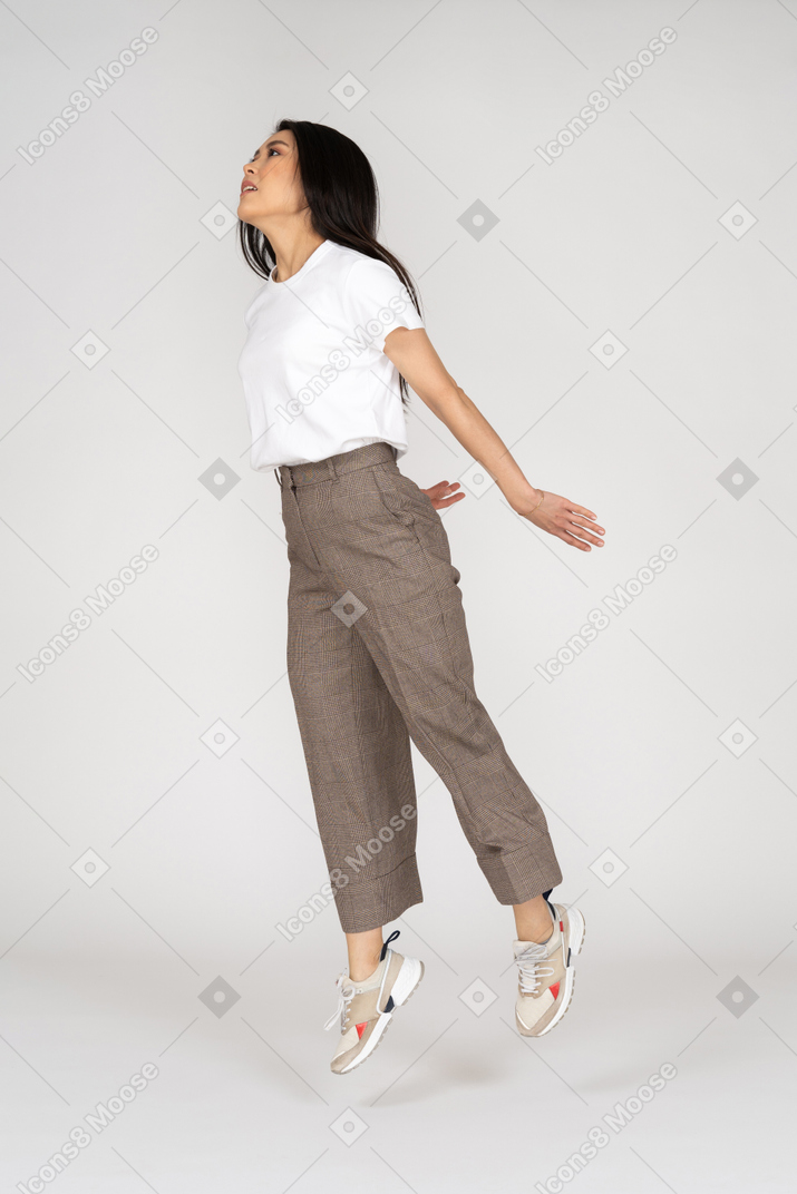 Three-quarter view of a jumping young lady in breeches and t-shirt