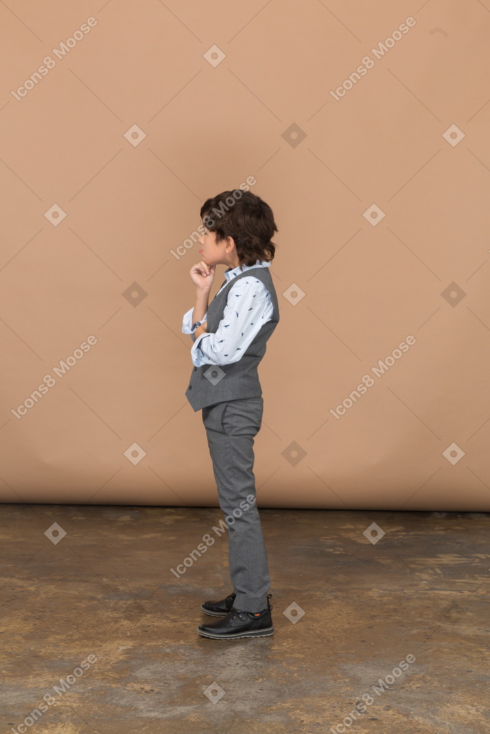 Vista lateral de un chico lindo pensativo en traje