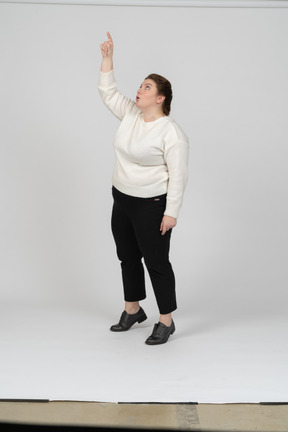 腕を上げて立っているカジュアルな服装のプラスサイズの女性の正面図
