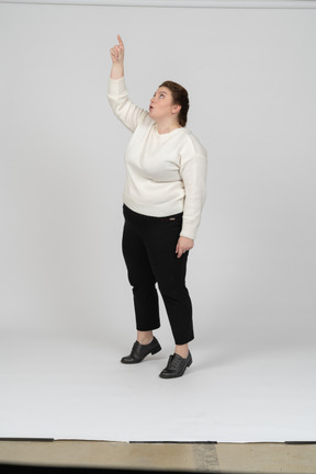 Front view of a plus size woman in casual clothes standing with raised arm