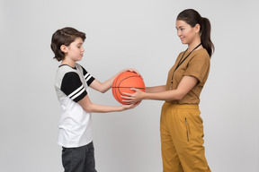 Profesora de pe y alumno sosteniendo una pelota de baloncesto