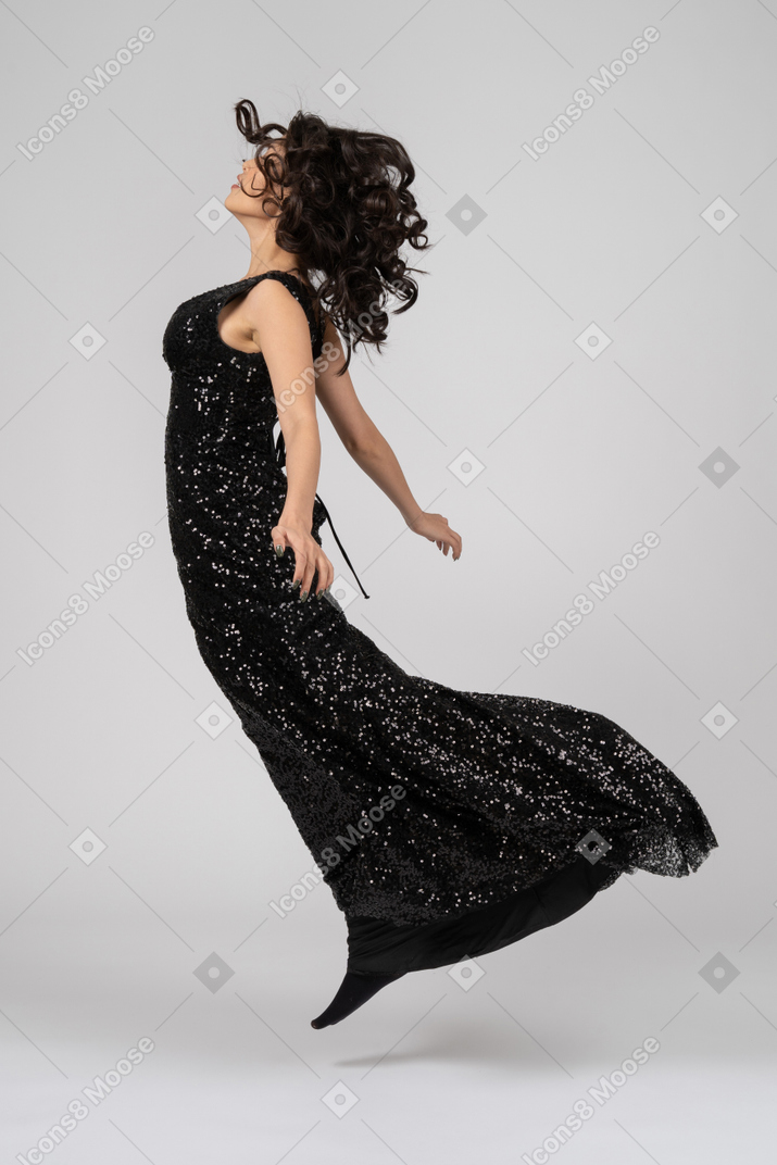 Beautiful woman in black evening dress jumps